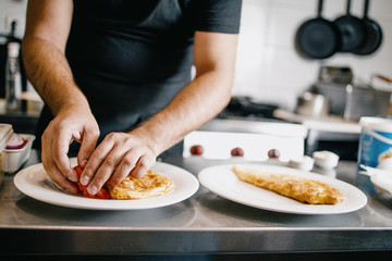 Professional chef working in restaurant kitchen and making delicious traditional food.