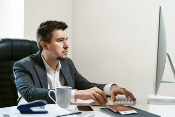 Thoughtful businessman at office workplace is typing text on a desctop computer keyboard. The idea of a new successful project. Financial analyst or IT specialist, sales manager, freelancer.