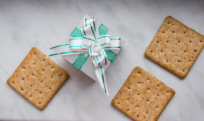 Flat lay. Top view. New Year's gift with bow of mint ribbons and lean ruddy crackers with bran on white background