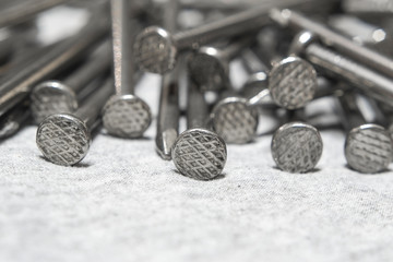 Head new steel nails on gray cloth close-up.