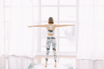 A girl in a tracksuit does sports at home. Exercise fitness stretching and yoga