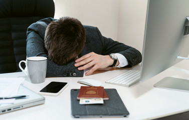 An overworked employee works on a desktop computer. Tired businessman or office worker sleeping at the workplace. Sales manager, financial analyst or IT specialist, freelancer.