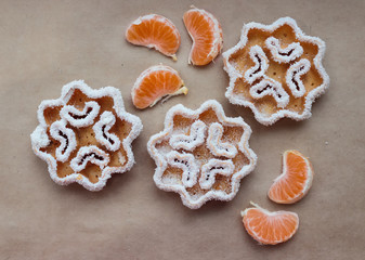 Christmas cookies in the form of snowflakes lie on baking paper with tangerines in chaotic order