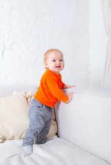 portrait of  small child, baby standing on a light sofa in the room,