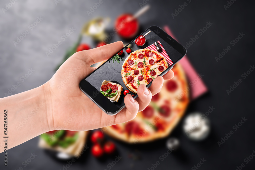 Wall mural blogger taking picture of delicious pepperoni pizza at table, closeup. food photography