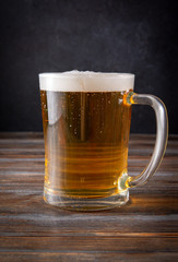  light barley beer with foam on a dark wooden background, alcoholic