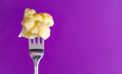 white cauliflower on a fork on a purple