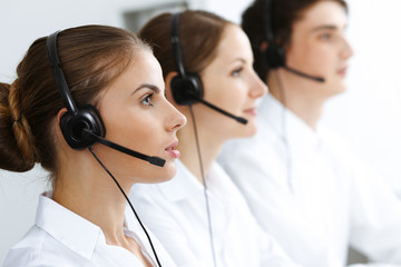 Call center. Beautiful young woman using headset and computer to help customers. Business concept