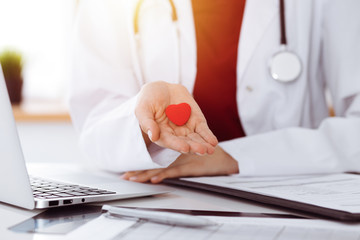 Unknown woman-doctor holding little heart in her hands in sunny room