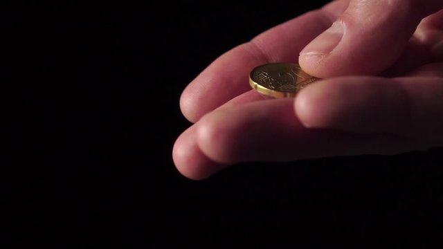 20 cents of European money in the palm on a black background close-up. The finger moves the coin. Slow motion. Concept of financial crisis after coronavirus and bankruptcy of a business
