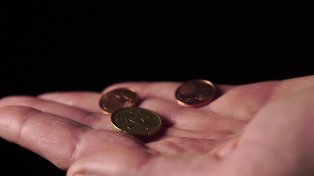 Coins of cents of European money falling on a palm on a black background close-up. Slow motion. The concept of unemployment and the financial crisis after coronavirus