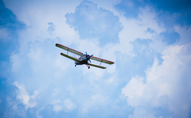 Biplane airplane flies in a picturesque cloudy sky. Old school aircraft aviation