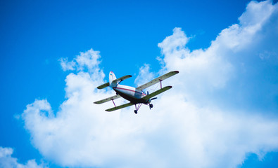 Fototapeta na wymiar Biplane airplane flies in a picturesque cloudy sky. Old school aircraft aviation
