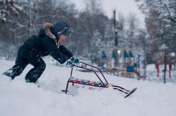 Caucasian child boy kid plays in deep plentiful snow. Winter games in childhood 
