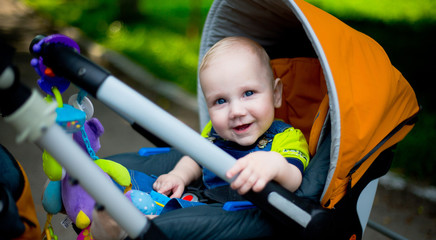 Fototapeta na wymiar Caucasian cute baby boy toddler smiling in a stroller outdoor