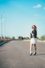 red-haired girl in a black jacket and blue glasses