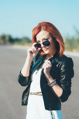 red-haired girl in a black jacket and blue glasses