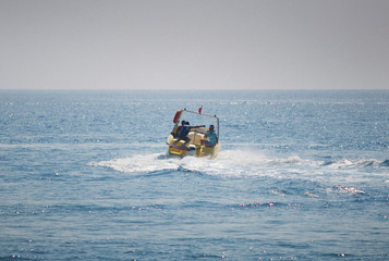 Fototapeta na wymiar Tourist speed boat rides tourists vacationing on the Mediterranean coast of Turkey