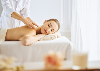 Obraz na płótnie Canvas Beautiful woman enjoying back massage with closed eyes. Spa treatment concept