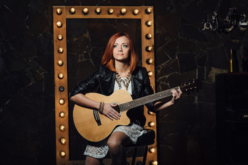 young girl with red hair with an acoustic guitar