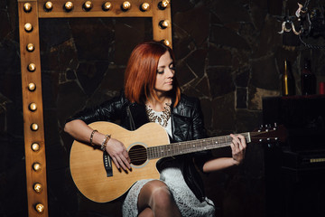 young girl with red hair with an acoustic guitar