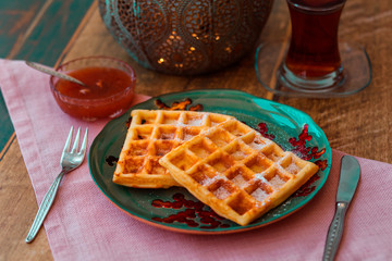 Waffles on a plate with tea and jam