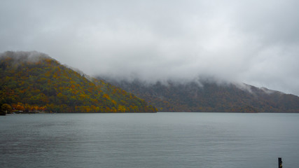 Beautiful view of Chuzenji lake and mountain with colorful autumn forest on cloudy sky background , copy space, Nikko