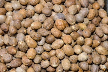 Heap of dry full nutmegs on open market. Fresh mace and nutmeg with selective focus