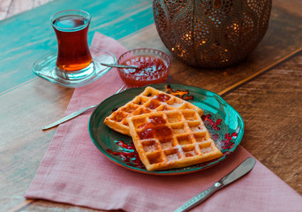 Waffles on a plate with tea and jam