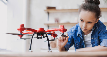 Young cute girl holding quadcopter. Child playing with drone at home. Education, children,...