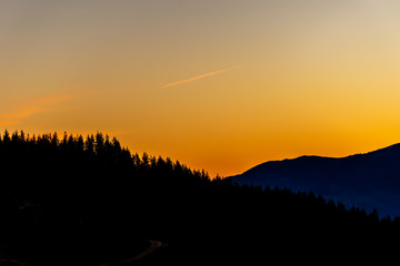 A picturesque landscape view of the silhouette of the French Pyrenees mountain range with tall pines on top early in the morning before sunrise (Col de Soum)