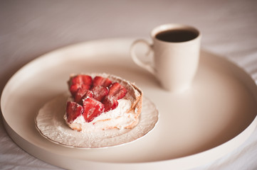 Cup of coffee with strawberry cake on white tray in bed closeup. Good morning. Breakfast time.