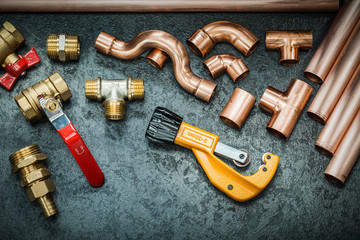 plumbers tools copper pipes fittings pipe cutter and valwes on black background