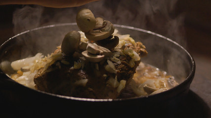 Preparing a pork with onions and mushrooms on the wood stove