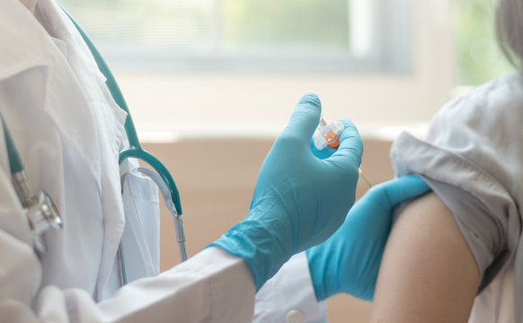 World immunization week and International HPV awareness day concept. Teenager woman having vaccination for influenza or flu shot or HPV prevention vaccine with syringe by nurse or medical officer.