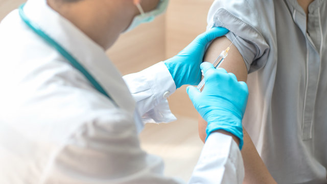 World immunization week and International HPV awareness day concept. Teenager woman having vaccination for influenza or flu shot or HPV prevention vaccine with syringe by nurse or medical officer.