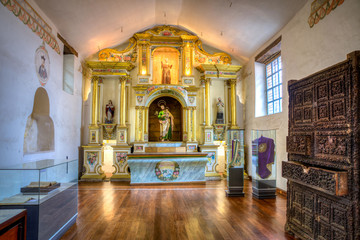 Fototapeta na wymiar Small sacristy inside the Sagrario Church, or Sanctuary Church, with many decorations, an altar, sculptures, windows and furniture.