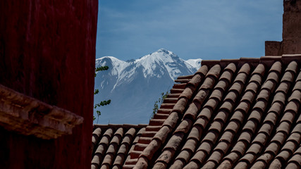 photo shows viewpoint from the latin america travel destination monasterio de santa catalina. view over roof tiles to the high snowcapped chachani volcano with blue sky.