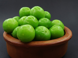 Green plums in a pottery bowl                               