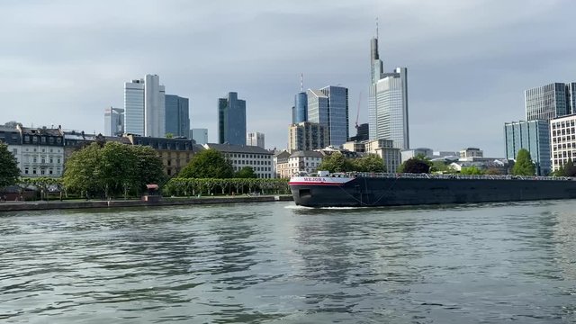 Frankfurt, Germany - 08th May 2020: A german photographer visiting the city, taking a video of a huge container ship drivers on the river Main with the skyline in the background.