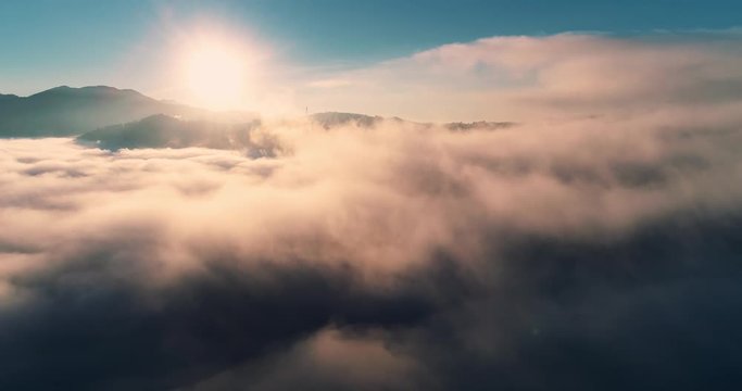 Aerial view flying through cumulus thunderclouds at sunrise. Gold colored sunset cloudiness in high contrast. Real sky. The concept of dreams and weather forecast. Сamera moves forward