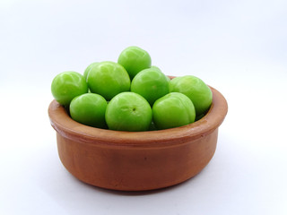 Green plums in a pottery bowl                               