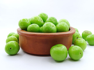 Green plums in a pottery bowl                               