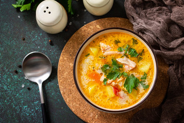 Norwegian Soup with cream and salmon on a rustic wooden table on a dark stone background. Top view flat lay background.