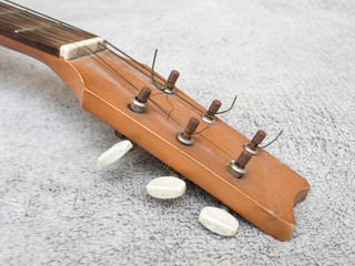 Detail of tuning head for old acoustic guitar. Head neck of classic acoustic guitar on gray...