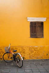 Fototapeta na wymiar An old Bicycle against a yellow wall with a wooden window in the old city of Hoi an. Place for the label.Vietnam.