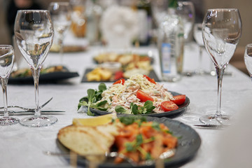Plates with salads on a table surrounded by glasses for wine.