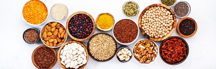 Various superfoods, legumes, cereals, nuts, seeds in bowls on white background. Superfood as chia,...