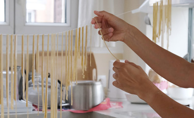une personne fait sécher des pâtes fraiches sur un fil