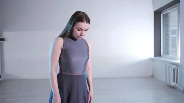young beautiful woman in a dress with long hair emotionally dancing contemporary, modern ballet dance in the studio with windows, slow motion, gimbal shot